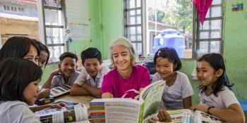 VSO Volunteer Ana Paula Pinto reads textbook and performs in classroom activity with the students from primary school at Kyakathone primary school, Myanmar