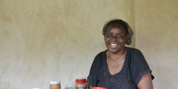Celina Chibanda smiles as she holds a large jar of the peanut butter she produces