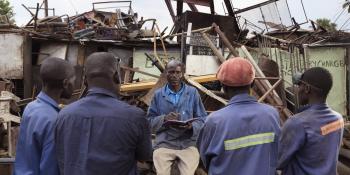 Peer educator Arthur instructs four other workmen in a junkyard
