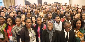 A large group of people stand together and smile for the camera, at the IVCO 2019 conference in Kigali