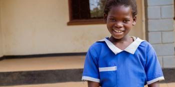 Young girl in blue dress smiles at the camera