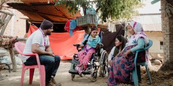 Volunteer talks to disabled girl and family