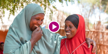 Two women from different ethnic backgrounds embrace.