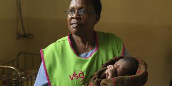 A VSO volunteer holding a newborn baby