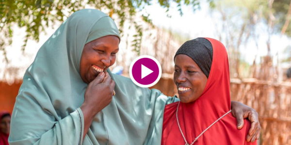Two women from different ethnic backgrounds embrace.