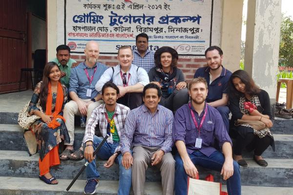 The Growing Together Team A group of people sat on stairs outside an office looking at the camera