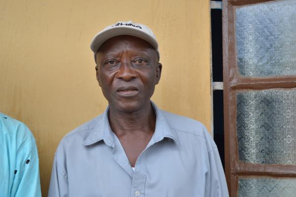 Ibrahim Kallan, a man who attended one of FINE Salone's husband schools, stands in front of his house