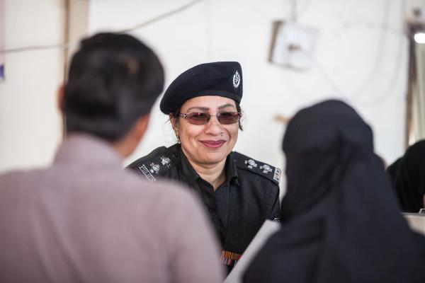 A female police officer smiles as she talks with a man and a woman