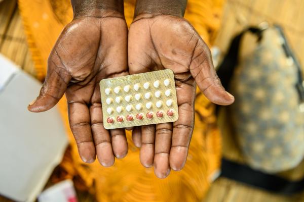 Close up of a woman's outstretched palms holding a packet of contraceptive pills