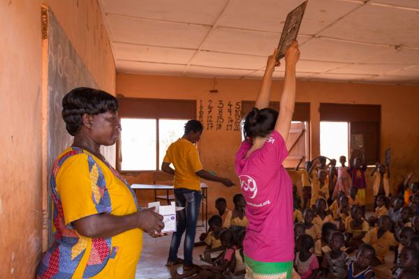 VSO volunteer Mary Carnable holds up a chalk slate in a classroom at Gaare Gbani School in Bolgatanga, where she helps disabled 7-year-old Jennifer Noabil as part of the Tackling Education Needs Inclusivelyproject. Talensi District, Ghana