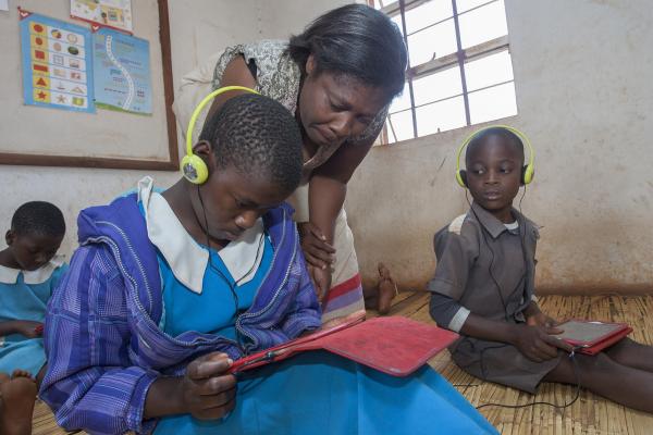 Standard two teacher Lynes Mussa assists eleven year-old pupil Halima Ali to work on her tablet during the Unlocking Talent Through Technology class session at Biwi Primary School in Lilongwe