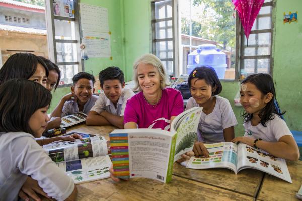 VSO Volunteer Ana Paula Pinto reads textbook and performs in classroom activity with the students from primary school at Kyakathone primary school, Myanmar