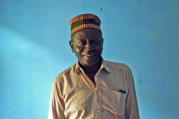 Local leader Chief Mohamed Possible stands in front of a bright blue wall