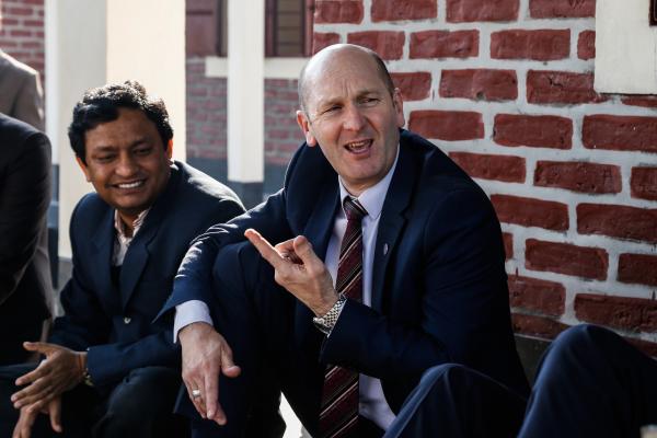 Phillip Goodwin, CEO of VEO, sits outside and talks with farmers in Bangladesh
