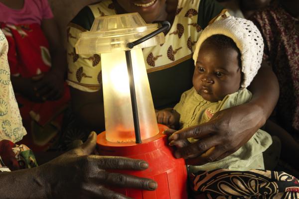 A baby looks transfixed at a solar lantern