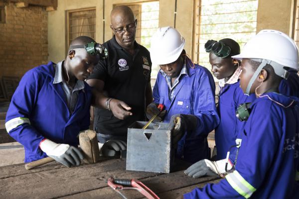 Volunteer Nobert oversees a small group of students in welding class