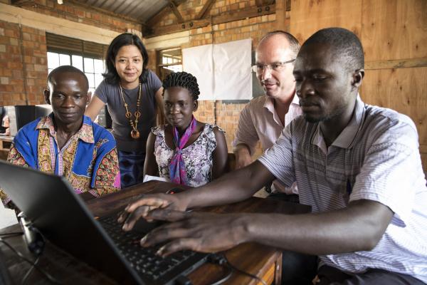 VSO international and corporate volunteers, along with staff from St Joseph's VTI, gather round a computer to learn about marketing