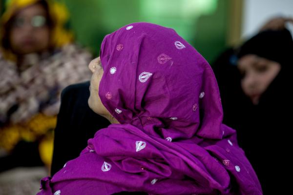 A woman in a colourful headscarf waits amongst other women at the police station