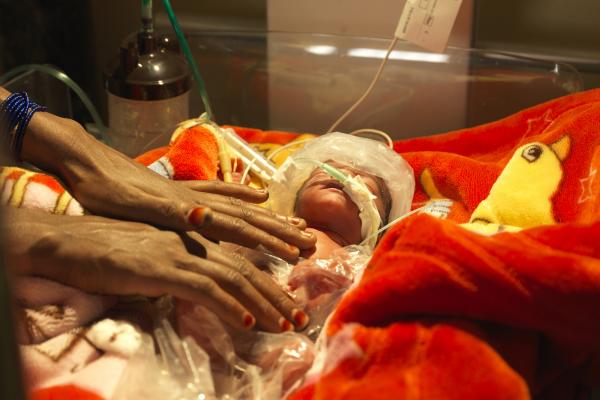 A newborn baby is warmed using a radiant warmer and insulated with plastic bags