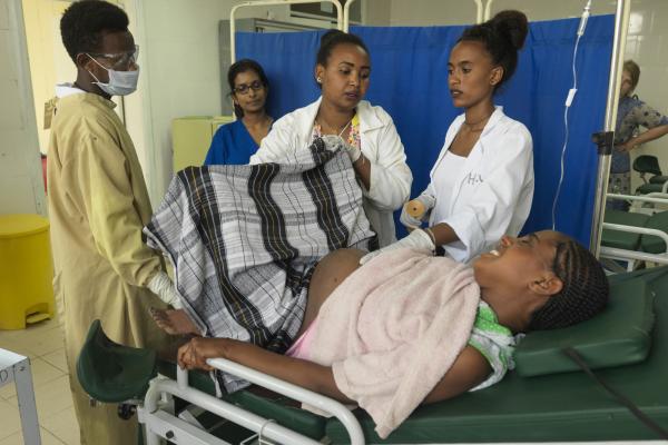 A group of doctors and midwives support a woman who is in labour