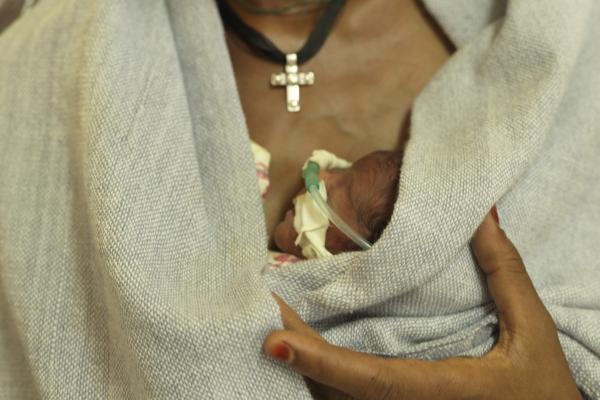 A mother holds her newborn premature baby against her chest