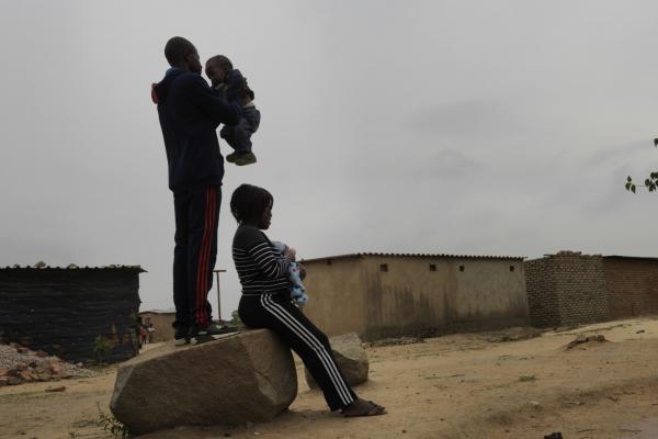 Brian and his wife Nyasha hold their young children in the street near their home in Harare