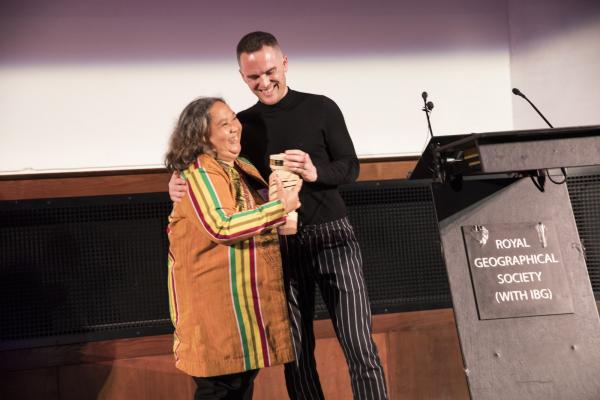 Impact Beyond Volunteering Award winner Ruby Yap smiles as she receives her award from David Atherton on stage