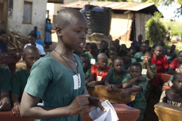 12-year-old Ayugi Monica stands in front of her classmates as she defends her point of view at an outdoor debate held at her primary school