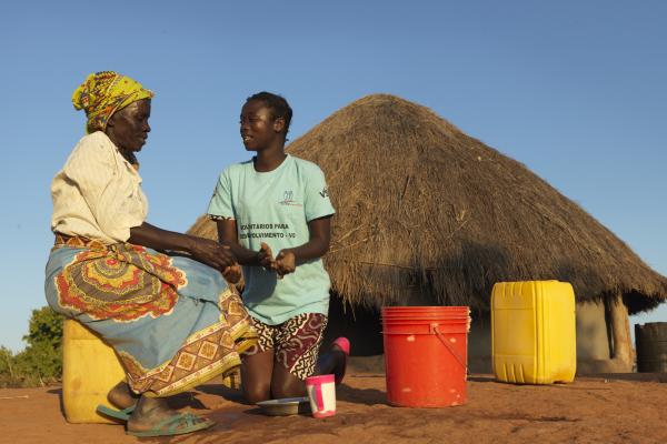Community volunteer Rosaria teaches local resident Gloria how to wash hands with ash, soap and water in a cholera prevention campaign after cyclone Idai