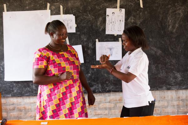 Volunteer in Rwanda. Mugirente Judith (left), a community health worker, taking part at the front of a a sexual reproductive health lesson with Niyonsaba Brown (right), a VSO national volunteer at Umutara School for Deaf children.