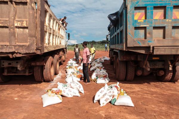 Volunteers unload sacks of food from two large trucks VSo/in Manjacure, Manica province.