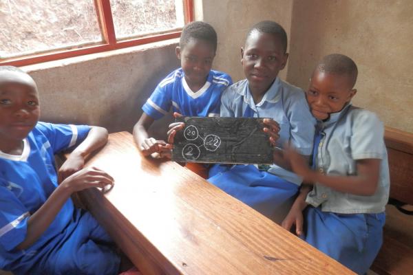 school children holding a small blackboard to the camera