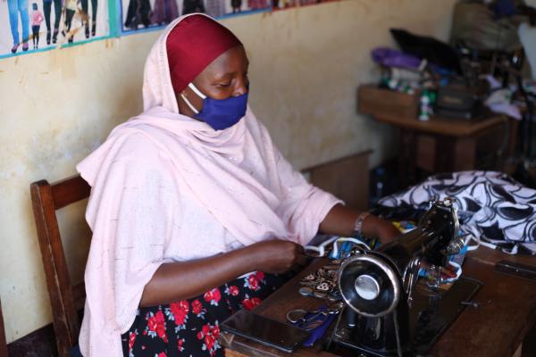 A woman using a sewing machine to make face masks