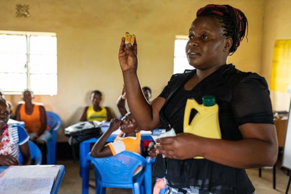 A woman standing at the front of a class giving a lesson