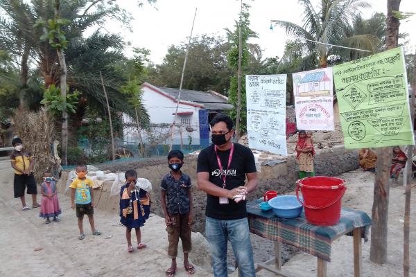 a man with a mask stood outdoors. He is next to a tap and educational posters