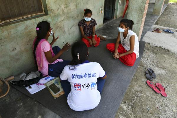 Two Big Sisters and two Little Sisters meet, sitting on the ground wearing face masks, to discuss staying safe and healthy during COVID-19