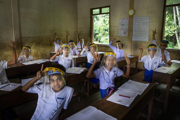 Children raise their hands in a Burmese classroom.
