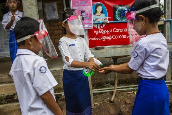 Children help to sanitise each other's hands after going back to school in Myanmar.