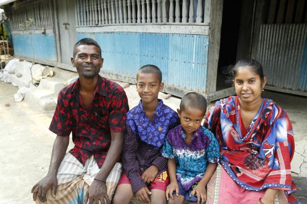 VSO-supported crab farmer Sathi Das sits outside with her husband and two sons
