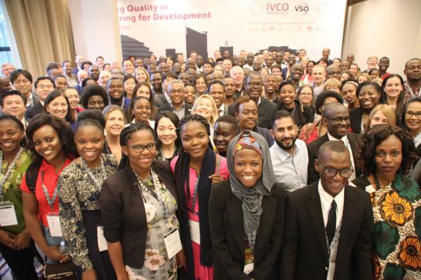 A large group of people stand together and smile for the camera, at the IVCO 2019 conference in Kigali
