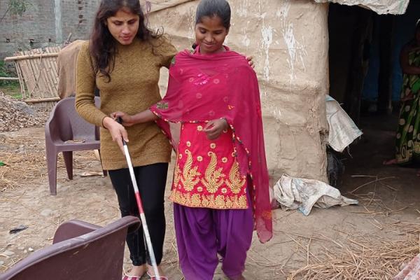 Anju teaches visually impaired girl how to walk with a cane.