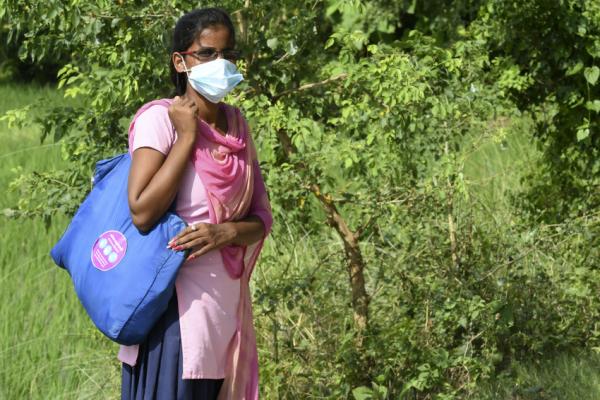 Nitu wearing a mask and carrying her bag of hygeine kits