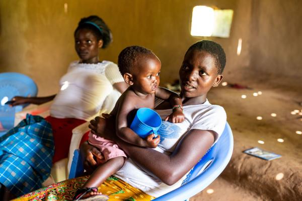 17-year-old Gladys in class at a catch-up centre in Kenya with her young baby on her lap