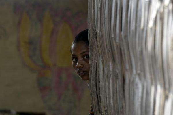 A young girl peeks around a corner with a worried experssion