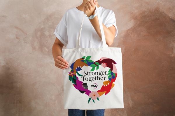 Tote bag says 'Stronger together' with the VSO logo. The text is surrounded by multi-coloured hands holding each other to form a heart.
