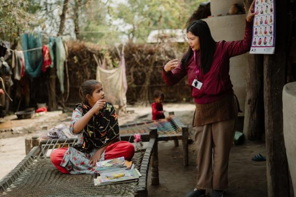 A volunteer teaches Inza, who was born with a hearing impairment, sign-language