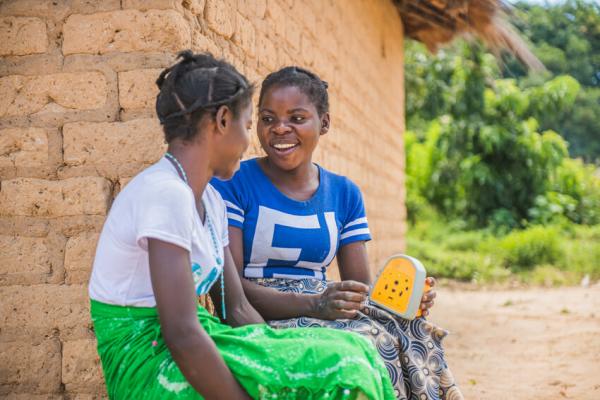 A VSO community volunteer and her sister listen to a a lesson on SRHR
