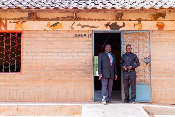 Artwel and primary school teacher, Peter, stood outside Peter's classroom