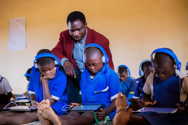 VSO volunteer Theo helping students use educational tablets.