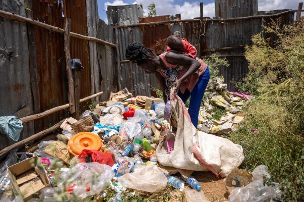 Woman holds baby while picking up litter